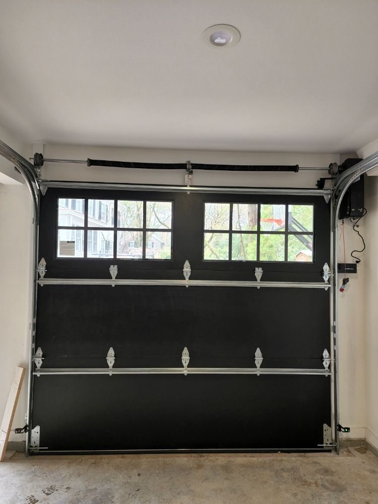 Interior of a black sectional carriage door with windows and carriage hardware