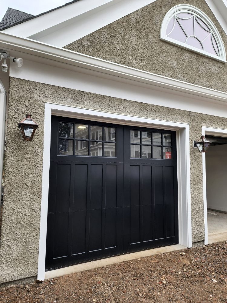 Black carriage-style garage door with divided-lite windows on a stucco home