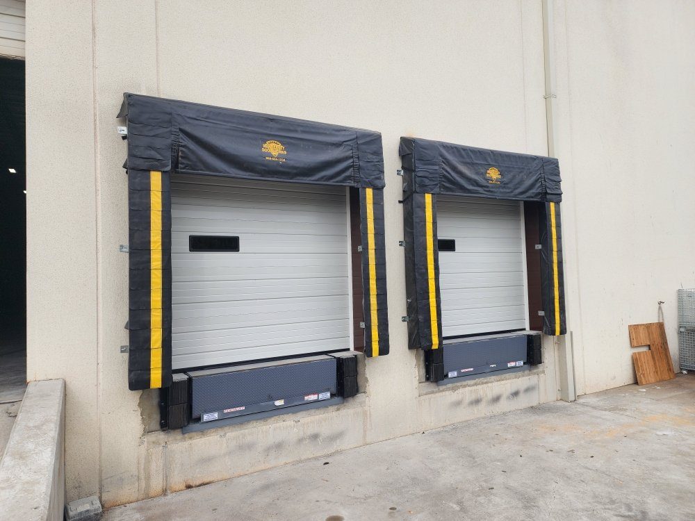 Two commercial insulated sectional dock doors with dock shelters and edge-of-dock levelers at a warehouse