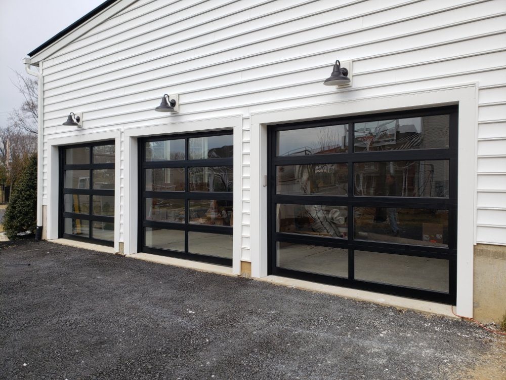 Three full-view black aluminum and glass garage doors on a detached garage