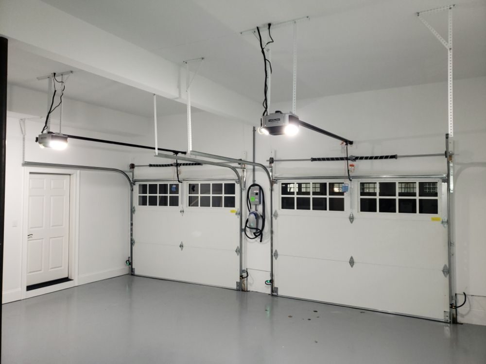 Two insulated sectional doors with LiftMaster openers and torsion spring assemblies in a finished garage