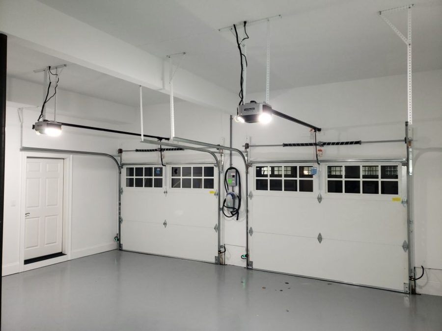 Two insulated sectional doors with LiftMaster openers and torsion spring assemblies in a finished garage
