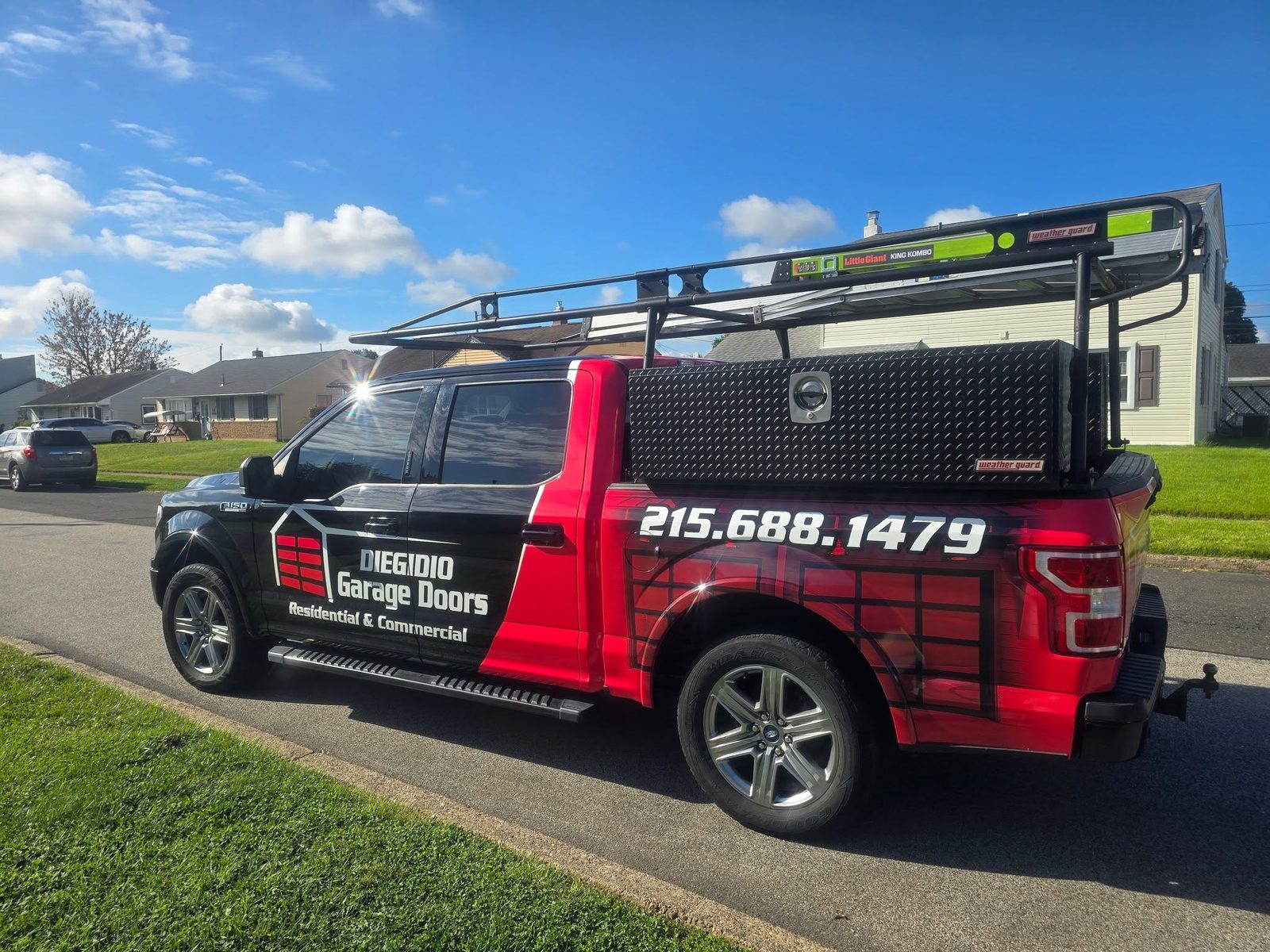The DiEgidio Garage Doors wrapped Ford F-150 service truck with ladder rack and tool box parked at a residential job